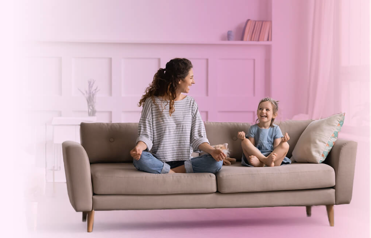 Madre e hija relajadas en un sillón beige.